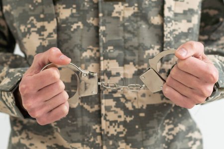 Photo for A military man is holding handcuffs. - Royalty Free Image