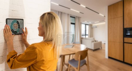 Mujer usando monitor de teléfono inteligente para controlar la interfaz de conectividad del hogar.