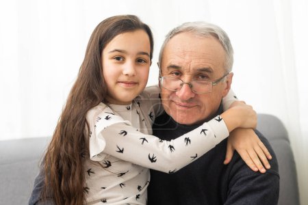 Foto de Anciano mayor de ochenta años hombre con nieta en un entorno hogareño - Imagen libre de derechos