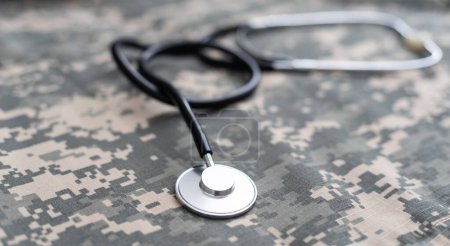 Stethoscope lies on the uniform of a US soldier. The concept of health care, military insurance, state care. Top view. Mixed media.