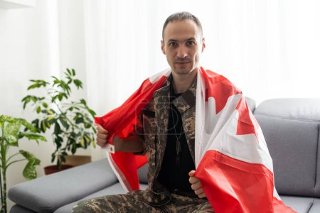 Foto de Hombre en uniforme militar sosteniendo bandera nacional de Canadá mientras - Imagen libre de derechos
