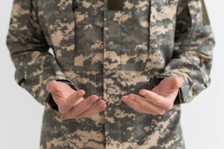 Primer plano disparo de manos de soldado irreconocible en uniforme camuflaje del ejército, militar.