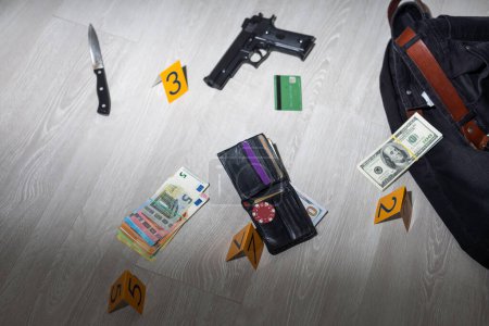 Photo for Crime scene investigation - numbering of evidences after the murdering in apartment. Brass knuckle, wallet and clothes with evidence markers. High quality photo - Royalty Free Image