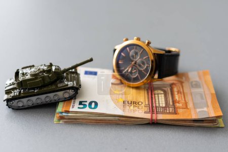 Economic crisis concept. Toy military tank on euro banknotes. War conflict in Ukraine, economic sanctions and inflation.