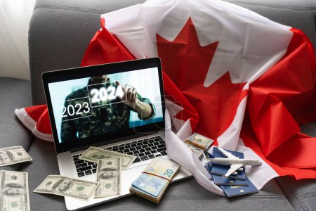 Foto de Portátil con avión, dinero y bandera de Canadá. - Imagen libre de derechos