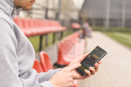 Photo for Man using online sports betting services on phone. - Royalty Free Image