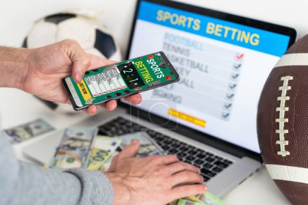 Man watching football play online broadcast on his laptop, cheering for his favourite team, making bets at bookmakers website. High quality photo