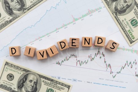 Conceptual image of the word dividend on letter cube with stock graph and dollar background. High quality photo