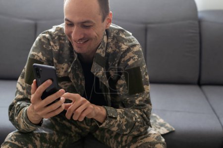 Shot of happy serviceman from ukraine with smartphone dressed in camouflage uniform. Information war. High quality photo