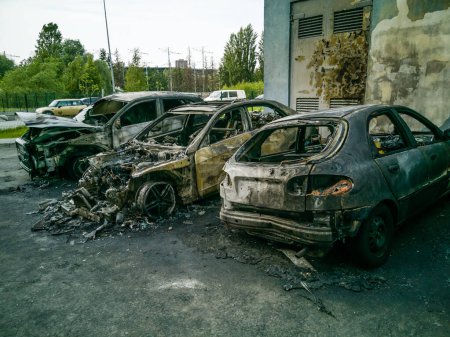 Téléchargez les photos : Des voitures brisées et incendiées dans le parking, un accident ou un vandalisme délibéré. Une voiture brûlée. Conséquences d'un accident de voiture. Dommages causés par un incendie criminel. Déversement de véhicules civils abattus par les troupes russes en Ukraine - en image libre de droit