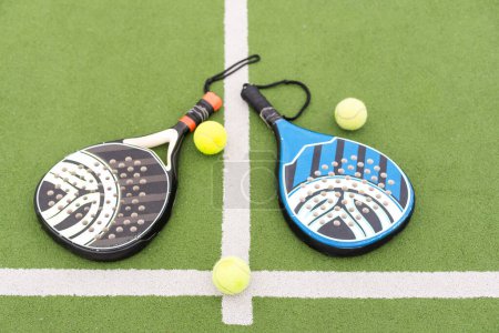 Photo for Yellow balls on grass turf near padel tennis racket behind net in green court outdoors with natural lighting. Paddle is a racquet game. Professional sport concept with copy space. High quality photo - Royalty Free Image