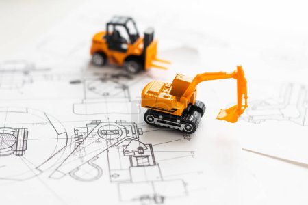 Téléchargez les photos : Tracteur jouet sur le plan de construction de logement. Photo de haute qualité - en image libre de droit