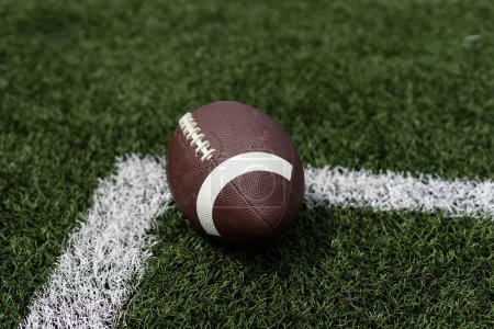 Close up view of an American Football sitting on a grass football field on the yard line. Generic Sports image . High quality photo