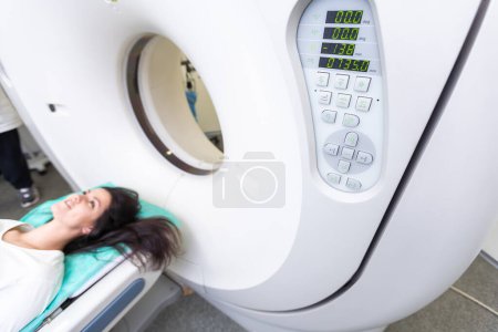 Photo for CT scan technologist overlooking patient in Computed Tomography scanner during preparation for procedure. Woman patient going into CT scanner - Royalty Free Image