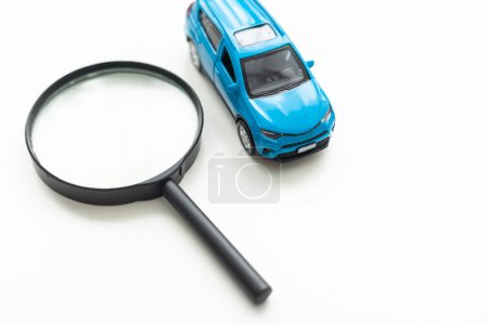 Téléchargez les photos : Modèle de voiture jouet et loupe sur fond blanc. Photo de haute qualité - en image libre de droit