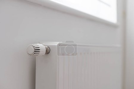 Téléchargez les photos : Un radiateur de chauffage à panneaux en acier est placé sous le rebord de la fenêtre sur un mur blanc. Photo de haute qualité - en image libre de droit