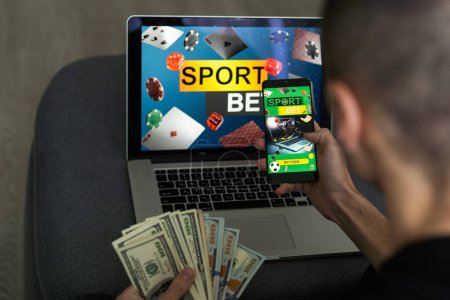 Man watching football play online broadcast on his laptop, cheering for his favourite team, making bets at bookmakers website.