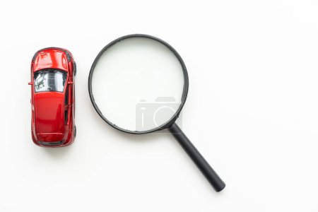 Téléchargez les photos : Modèle de voiture jouet et loupe sur fond blanc. Photo de haute qualité - en image libre de droit
