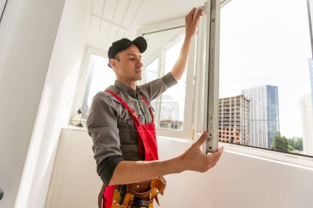 Photo for Young repairman fixing window frame in room at daytime. High quality photo - Royalty Free Image
