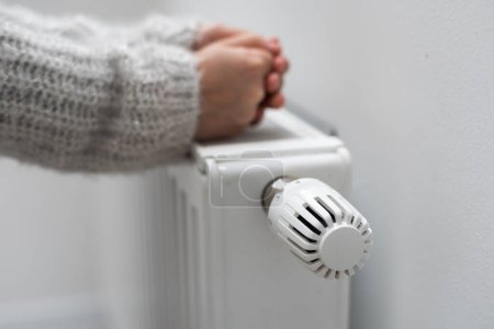 Photo for The childs hands warm their hands near the heating radiator. Saving gas in the heating season - Royalty Free Image