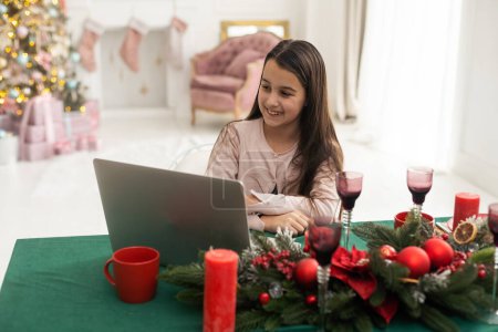 Photo for Teenage girl with gifts and laptop near the Christmas tree. Living room interior with Christmas tree and decorations. New Year. Gift giving - Royalty Free Image