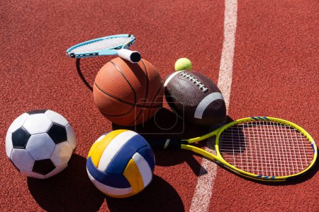 Photo for A variety of sports equipment including an american football, a soccer ball, a tennis racket, a tennis ball, and a basketball. - Royalty Free Image