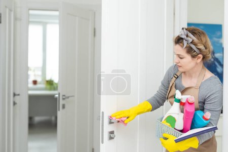 Photo for Weekend homework. Young pretty woman cleans in cozy living room at home. A beautiful woman in home clothes and rubber gloves in a bright room - Royalty Free Image