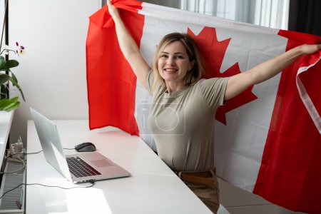 Téléchargez les photos : Étudiante assise avec le drapeau canadien et utilisant un ordinateur portable. Photo de haute qualité - en image libre de droit