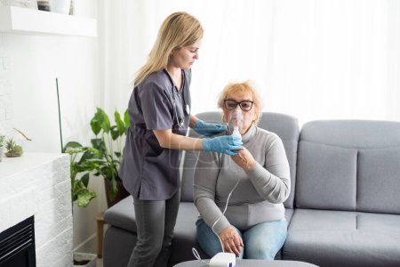 Téléchargez les photos : Femme âgée utilisant un inhalateur pour l'asthme et les maladies respiratoires à la maison. - en image libre de droit