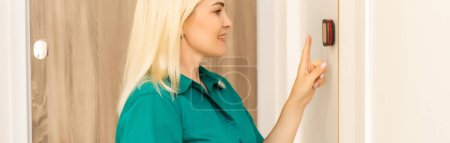 Téléchargez les photos : Smart home écran tactile thermostat numérique femme tactile écran tactile pour ajuster la température de chauffage dans le mur du salon. - en image libre de droit