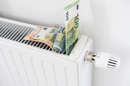Téléchargez les photos : Billet de banque couché sur le radiateur, le concept de hausse des prix de l'énergie et de chauffage plus cher. Photo de haute qualité - en image libre de droit