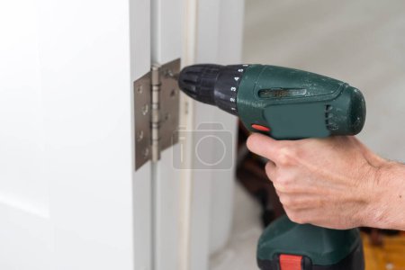 Téléchargez les photos : Un homme réparant la poignée de porte dans le salon. Photo de haute qualité - en image libre de droit