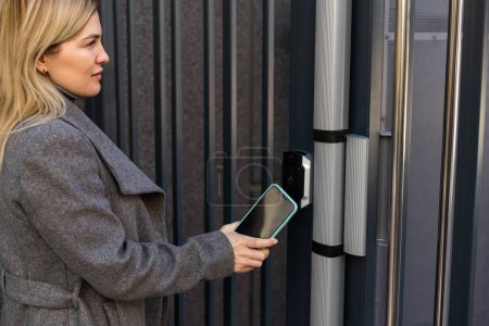 Téléchargez les photos : Les mains de femme utilisant le balayage de téléphone aux systèmes de sécurité numériques de serrure de porte à la maison - en image libre de droit