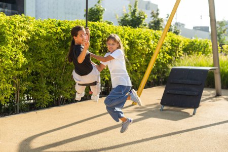 Téléchargez les photos : Petites filles caucasiennes appréciant à aire de jeux extérieure pour enfants. Petites filles jouant au parc. Photo de haute qualité - en image libre de droit