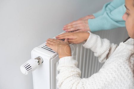 Photo for Girl warm ones hands near radiator at home - Royalty Free Image