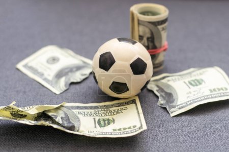Foto de Pequeña pelota de fútbol en un montón de dólares aislados sobre un fondo blanco. Foto de alta calidad - Imagen libre de derechos