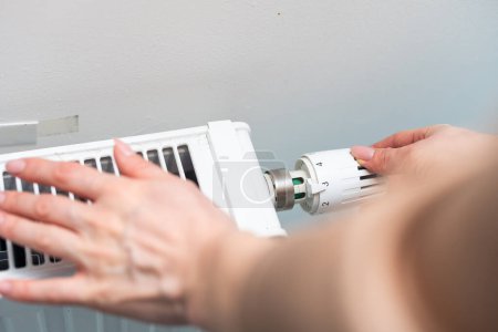Pomo del radiador de calor. Mujer ajustando a mano la temperatura en el radiador de calefacción. Foto de alta calidad