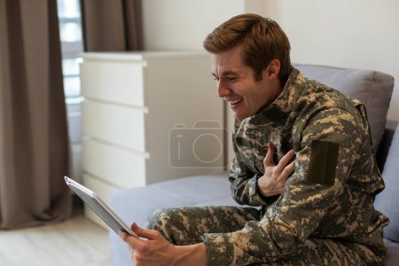 Militärangehörige winken. Militärangehöriger winkt bei Videochat mit Familie auf Tablet.