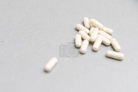 Gran número de pastillas blancas dispersas en una superficie gris. Concepto médico mínimo, farmacéutico con espacio de copia gratuito. Foto de alta calidad