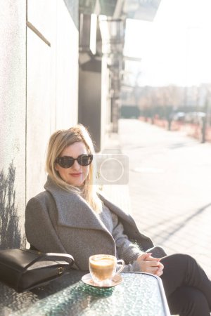 Jeune femme d'affaires caucasienne boit du café sur la terrasse du café. Photo de haute qualité