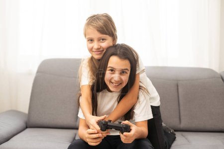 Photo for Two sisters kids playing video games at home together. Happy childeren, carefree childhood concept. High quality photo - Royalty Free Image