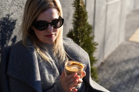 Young caucasian woman business woman drinks coffee at coffee shop terrace. High quality photo