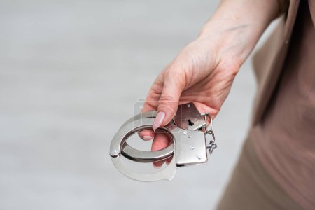 Womans hand holding handcuffs isolated on white. High quality photo
