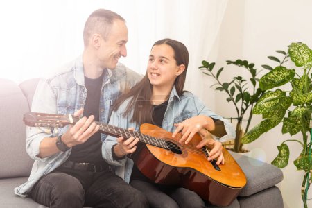 Photo for Smiling father showing daughter how to play barre chord. High quality photo - Royalty Free Image