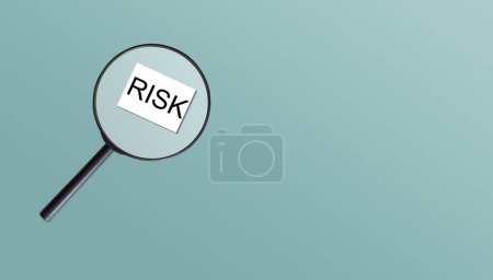 A magnifying glass against white background increases the word Risk. High quality photo