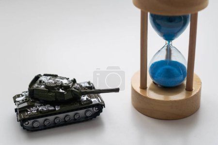 The plastic tank toys on the floor next to an hourglass. High quality photo