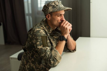 Ein deprimierter Armeeangehöriger in Uniform sitzt in einem leeren Raum. Platz für Ihr Poster an der Wand. Hochwertiges Foto