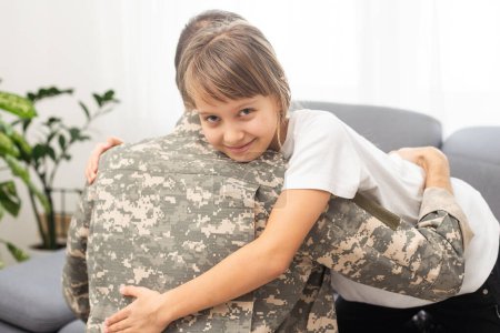Petite fille embrassant son père militaire à la maison, gros plan. Photo de haute qualité