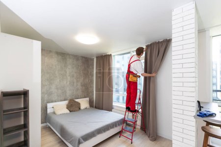 A male worker who installs a curtain