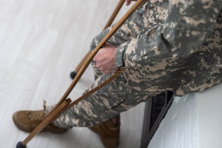 soldado en uniforme militar caqui con muletas.